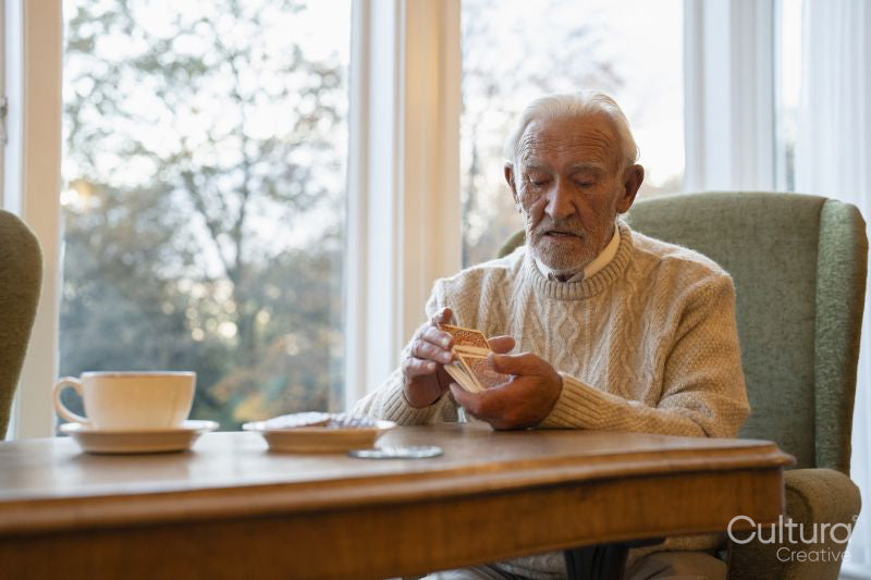 Senior man sitting at table and shuffling cards