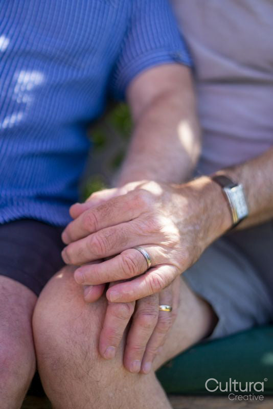 Senior male couple holding hands with wedding rings