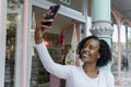 Smiling woman taking selfie in front of building