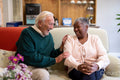Smiling senior man and woman sitting on sofa in nursing home