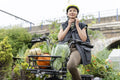 Smiling woman fastening helmet on cargo electric trike with homegrown vegetables