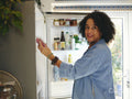 Portrait of woman opening fridge