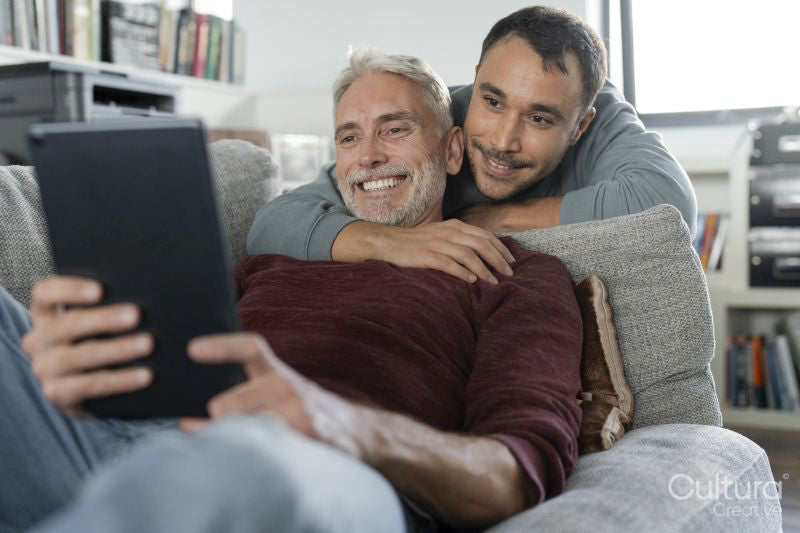 Smiling male couple using digital tablet on sofa