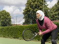 Sutton,Woman in headscarf playing tennis in park