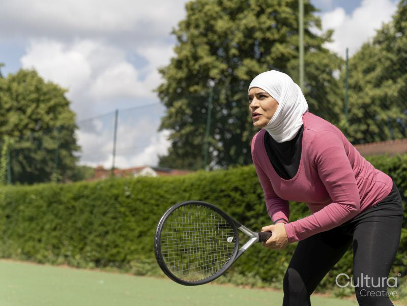 Sutton,Woman in headscarf playing tennis in park