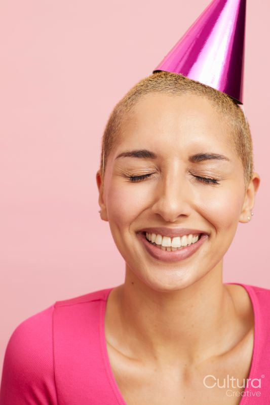 Young woman wearing party hat, laughing