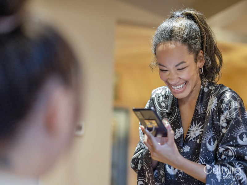 Woman looking at friend using phone at home