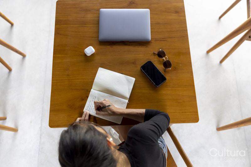 Woman sitting at table and writing, overhead view
