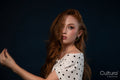 Woman in a polka dot top posing with arm raised in a studio