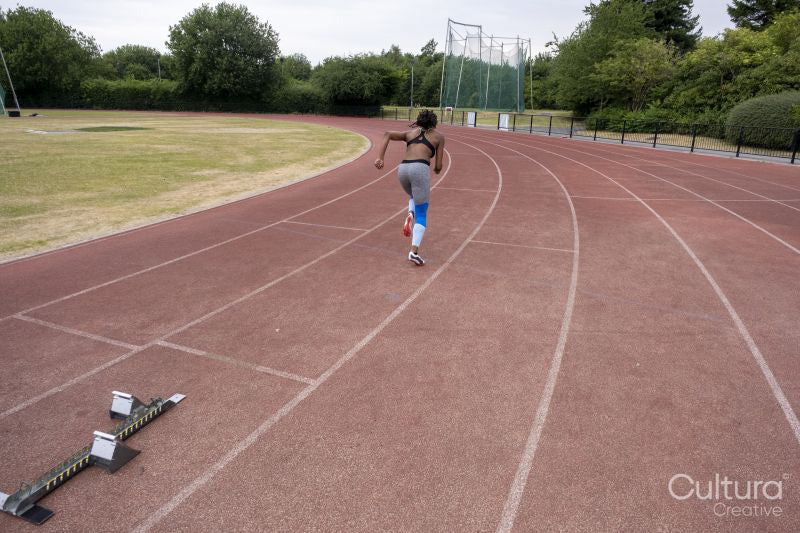 Rear view of athletic woman running on track