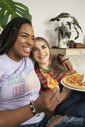 Two young women sitting on sofa eating pizza