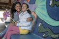 Smiling mother and daughter sitting in tunnel with graffiti