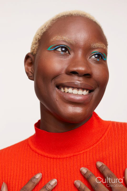 Smiling woman with short white hair and blue make up, looking up