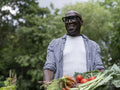 Smiling mature man holding vegetables from garden