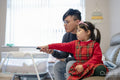 Father and daughter using remote control together