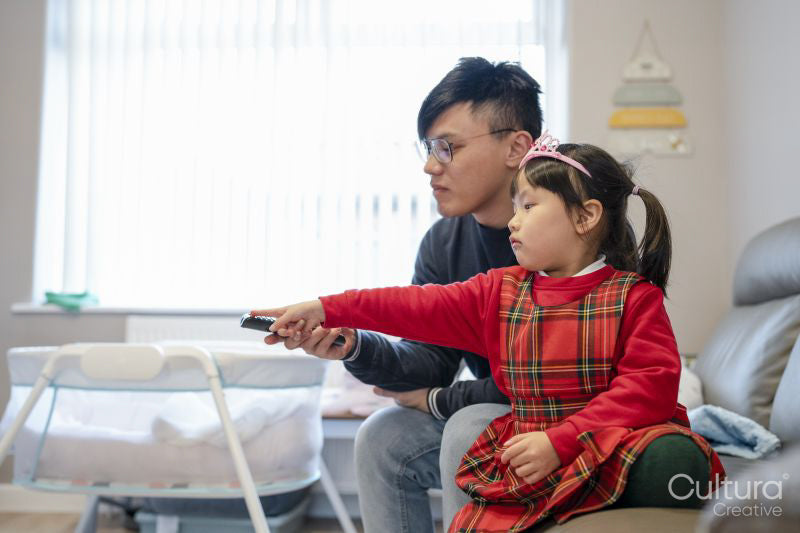Father and daughter using remote control together