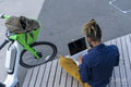 Businessman sitting by rental bicycle and using laptop