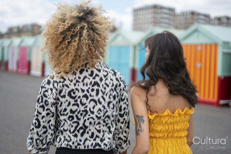 Female couple strolling by beach huts