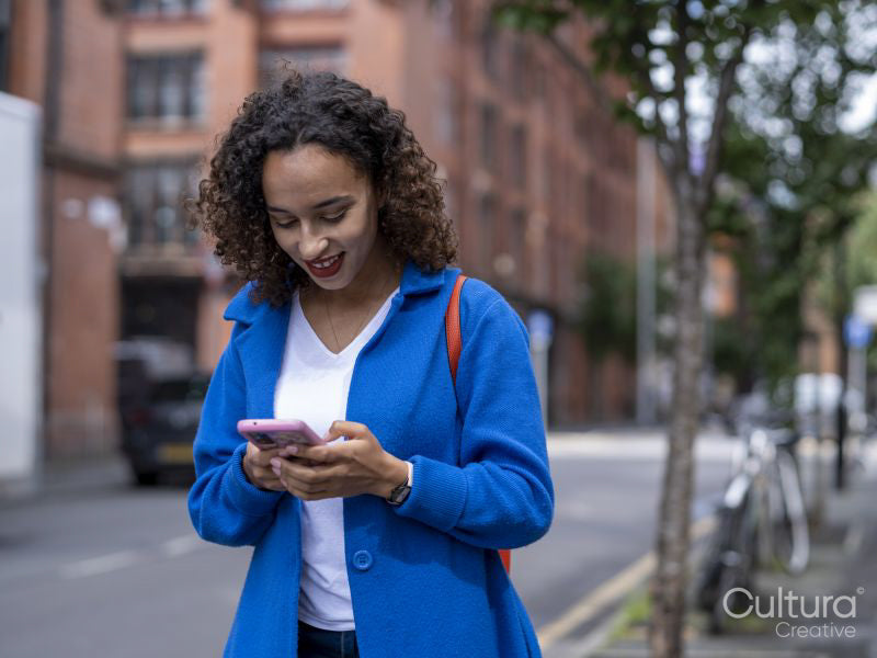 Smiling woman using smart phone on street