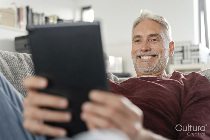 Smiling mature man using digital tablet on sofa