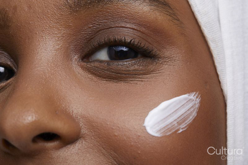 Studio portrait of young woman in white hijab applying face cream