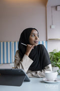 Young woman in hijab working on tablet in cafe