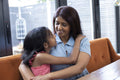 Smiling mother embracing daughter at home