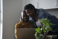 Man and pregnant woman looking at laptop in kitchen