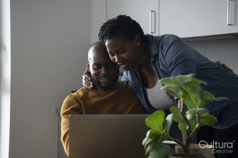 Man and pregnant woman looking at laptop in kitchen