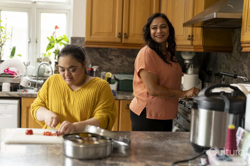 Woman with down syndrome preparing food with mother in kitchen