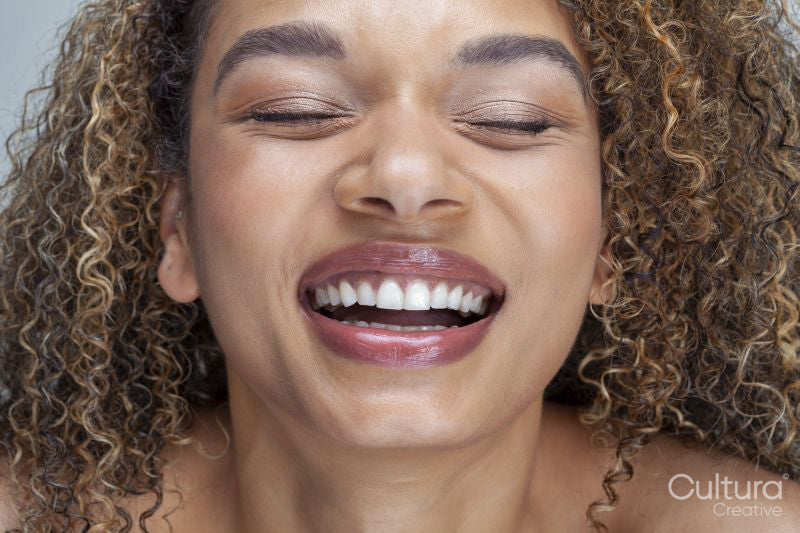 Close-up of smiling woman with curly hair and eyes closed