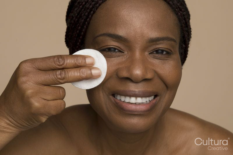 Studio portrait of mature woman cleaning face with cotton pad