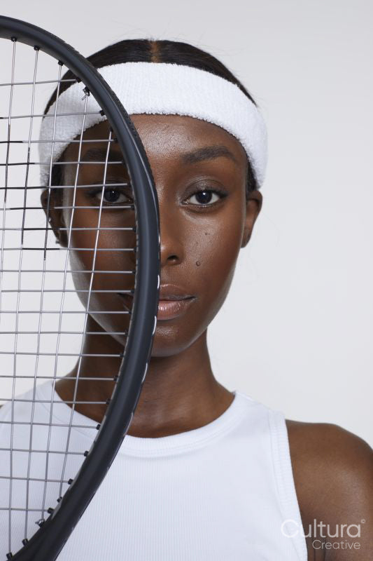 Studio portrait of athletic woman with tennis racket