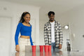Friends playing beer pong at home party