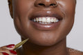 Close-up of smiling woman with tweezers