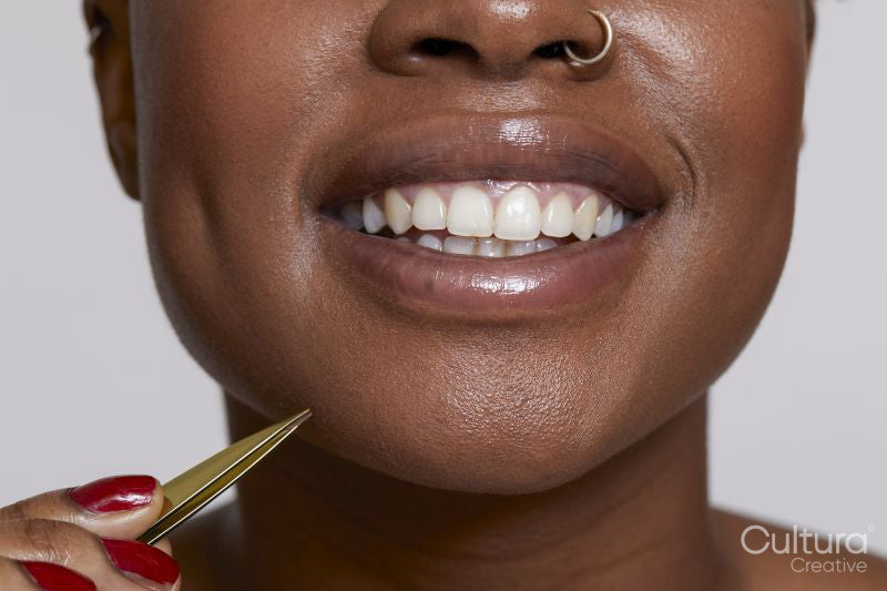 Close-up of smiling woman with tweezers