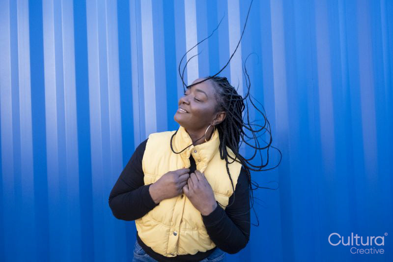South Yorkshire, Smiling woman with long braided hair against striped wall