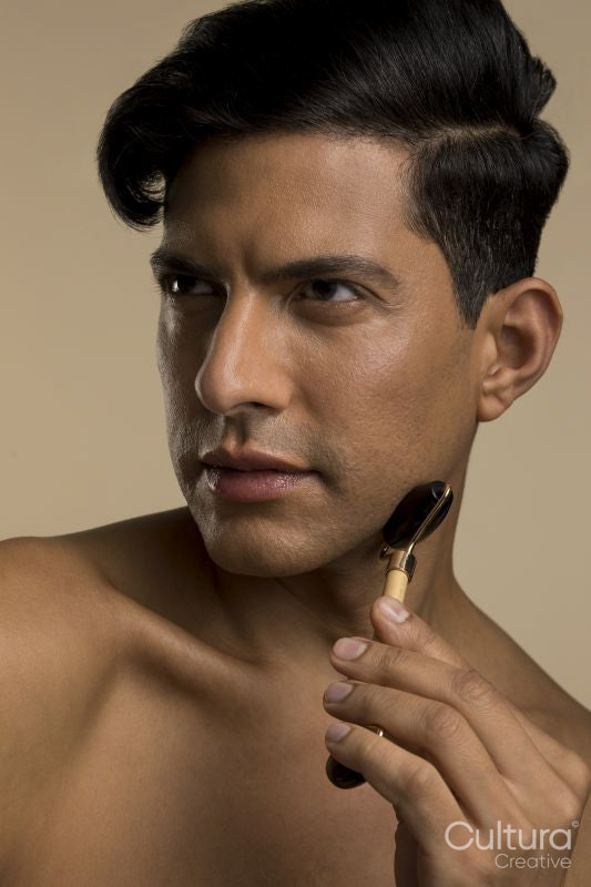 Studio portrait of man using face roller