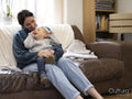 Son with cerebral palsy sitting on mothers lap at home