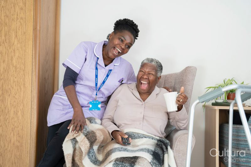 Caregiver and senior woman watching TV and laughing
