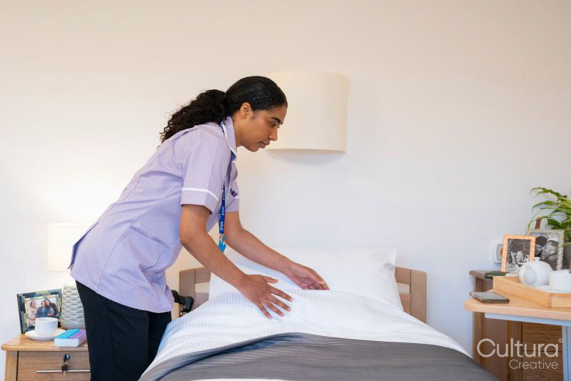 Nurse making bed in room at nursing home