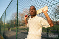 Portrait of cricketer leaning on fence on outdoors sports court
