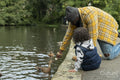 Father with daughter feeding duck on pond in park