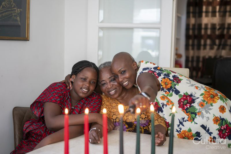 Teenage girl with mother and grandmother at table with Kwanzaa candles