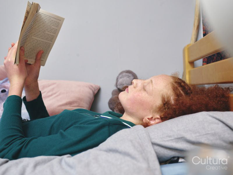 Girl reading book on bed