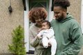 Parents holding baby daughter in front of home