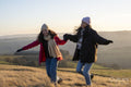 Smiling female friends hiking in rural landscape and holding hands