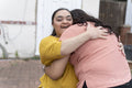 Woman embracing down syndrome daughter in front of house