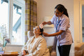 Nurse brushing hair of senior lady at nursing home