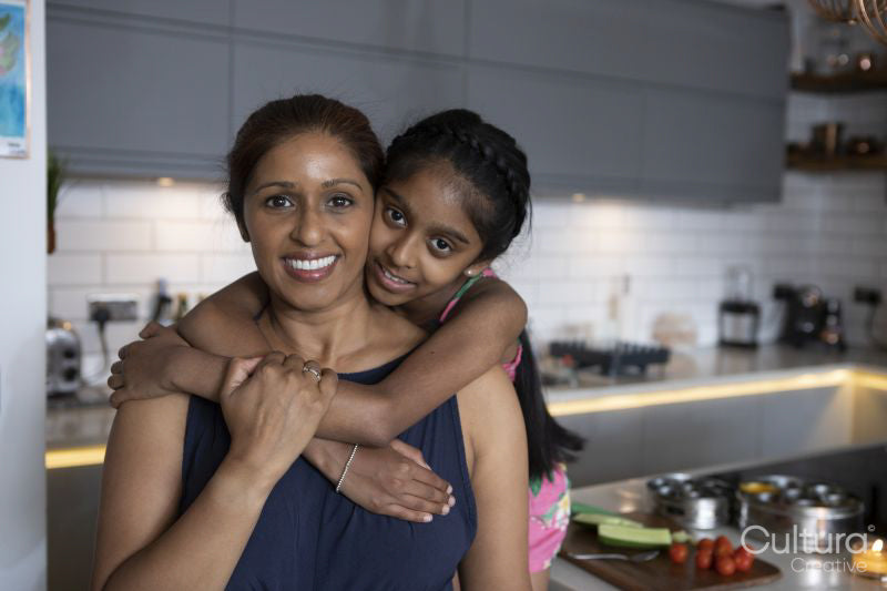 Portrait of girl embracing mother in kitchen